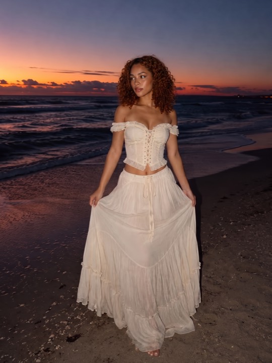 A woman photographed on a beach, framed full body with her feet at the bottom edge.