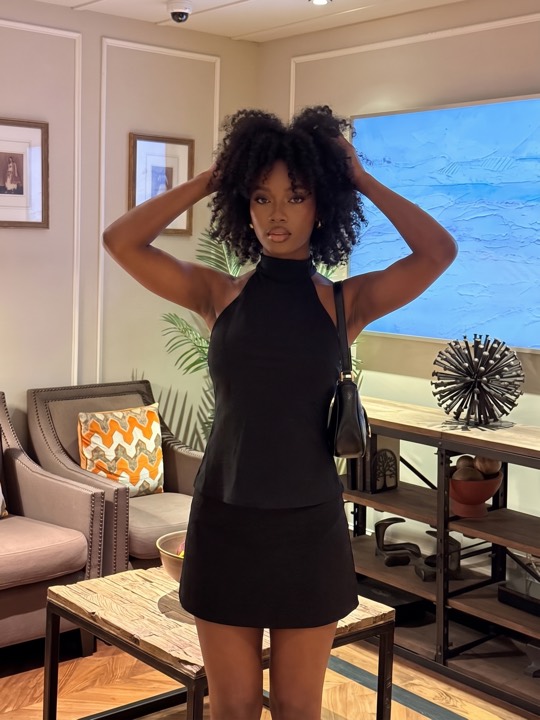 A woman photographed in a hotel setting, framed from the waist up with space above her head.