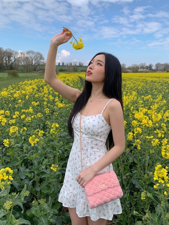 A woman outdoors in nature, framed from the waist up and placed off centre.